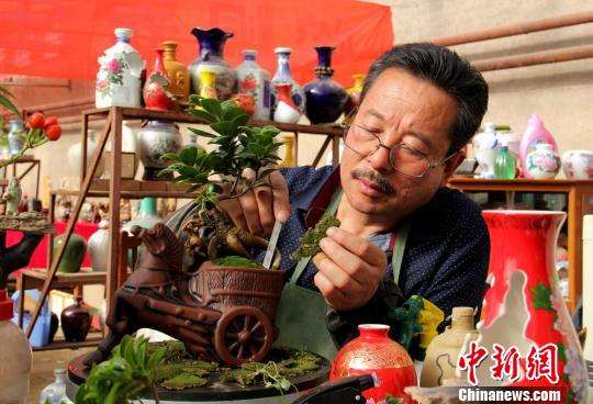 图为正在制作艺瓷盆景“马上封‘猴’”。郭惠民　摄
